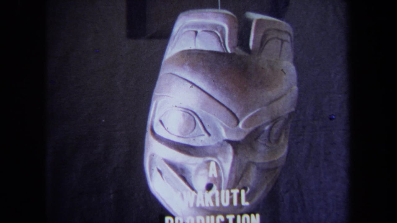 1971 California 8mm frame showing a pale carved mask with stylized eyes and partial text reading “A KWAKIUTL PRODUCTION.”