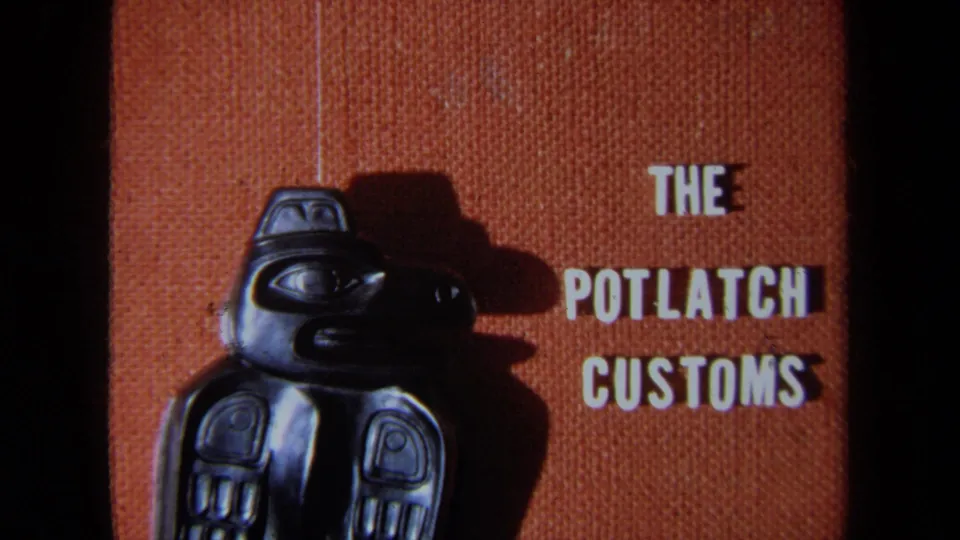 1971 California 8mm frame with a dark carved totem-style figure, side shadow, and white block title text reading The Potlatch Customs.