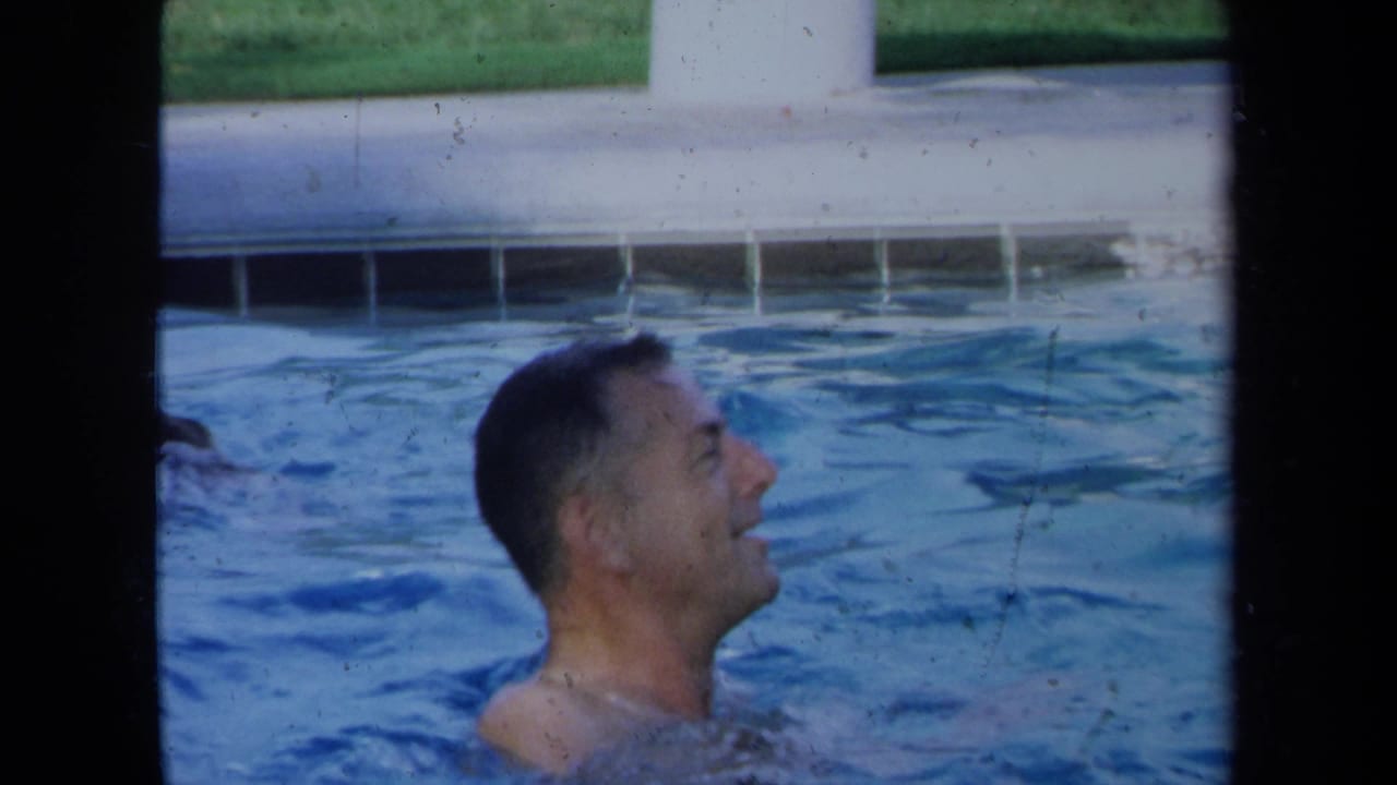 Adult man smiles while swimming in a California pool in 1971 home-movie footage.