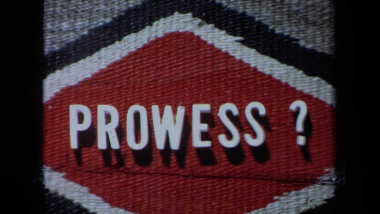 Close-up of a red-and-white “PROWESS?” sign on textured material, seen in the 1971 poolside home movie.