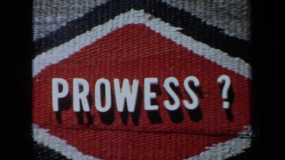 Close-up of a red-and-white “PROWESS?” sign on textured material, seen in the 1971 poolside home movie.