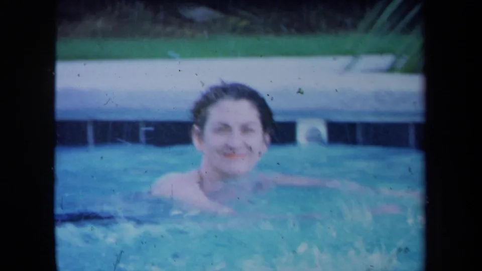 1971 California 8mm frame showing a wet-haired adult woman smiling toward the camera from a backyard swimming pool.