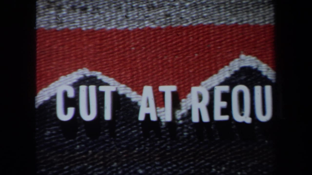 Home-movie title or editing card with red and dark woven texture and partial white lettering reading CUT AT REQU.