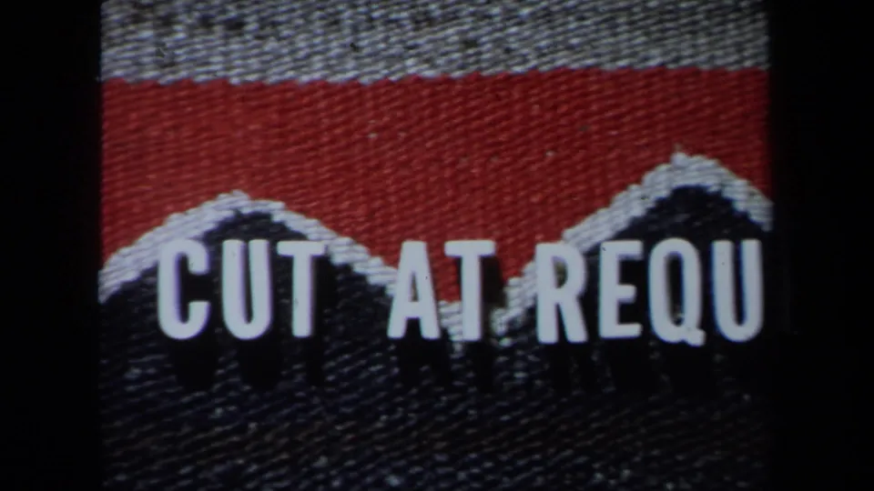 Home-movie title or editing card with red and dark woven texture and partial white lettering reading CUT AT REQU.