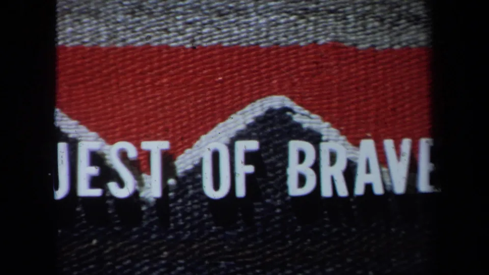 1971 California home-movie frame with cropped text reading parts of words on textured red and black fabric.