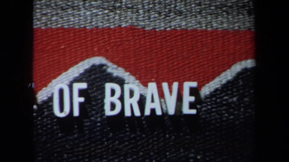 8mm frame from 1971 California showing cropped white lettering, including part of 'OF BRAVE,' on a woven fabric graphic.