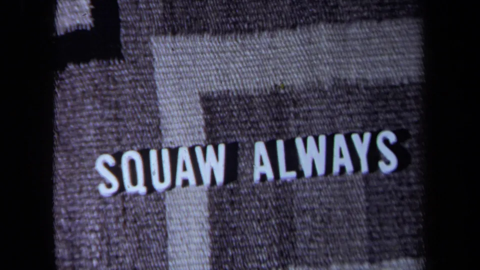 1971 California 8mm frame showing “SQUAW ALWAYS” in white block letters on gray patterned woven fabric.
