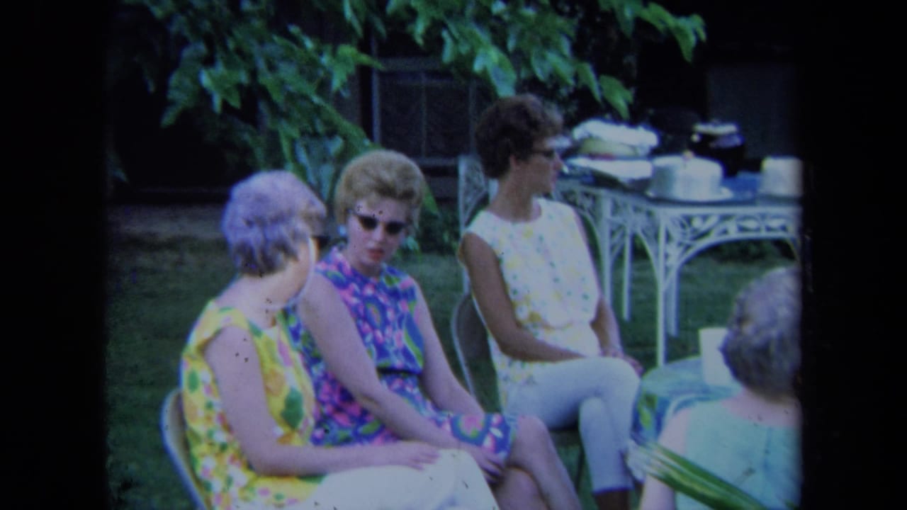 Women sit in lawn chairs in a yard with a white metal table behind them.