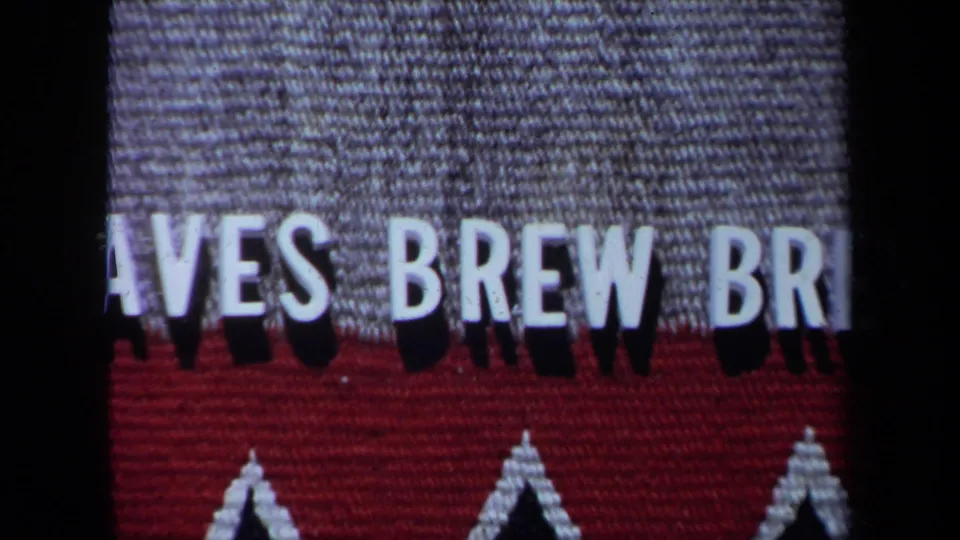 Tightly framed 8mm shot of the Braves Brew Brew sign, with cropped white lettering and red fabric-like texture.