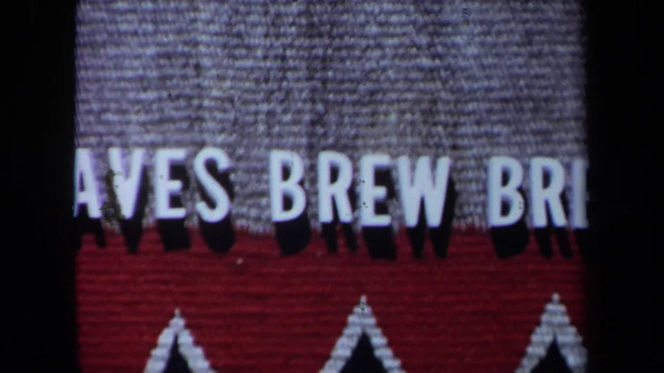 Close 1971 home-movie frame of the red and gray Braves Brew Brew sign, cropped so only part of the phrase is visible.