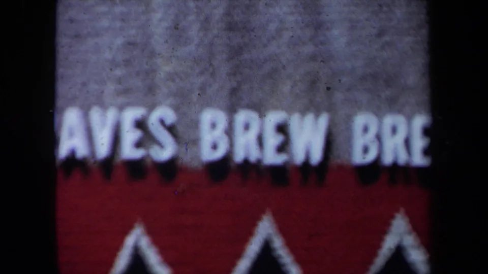 1971 California 8mm frame showing blurred cropped white sign text above a red band and white triangular border detail.