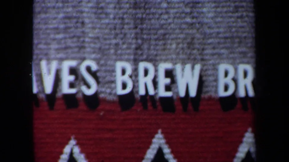 1971 California home-movie still of cropped white sign lettering becoming sharper against gray and red sections.