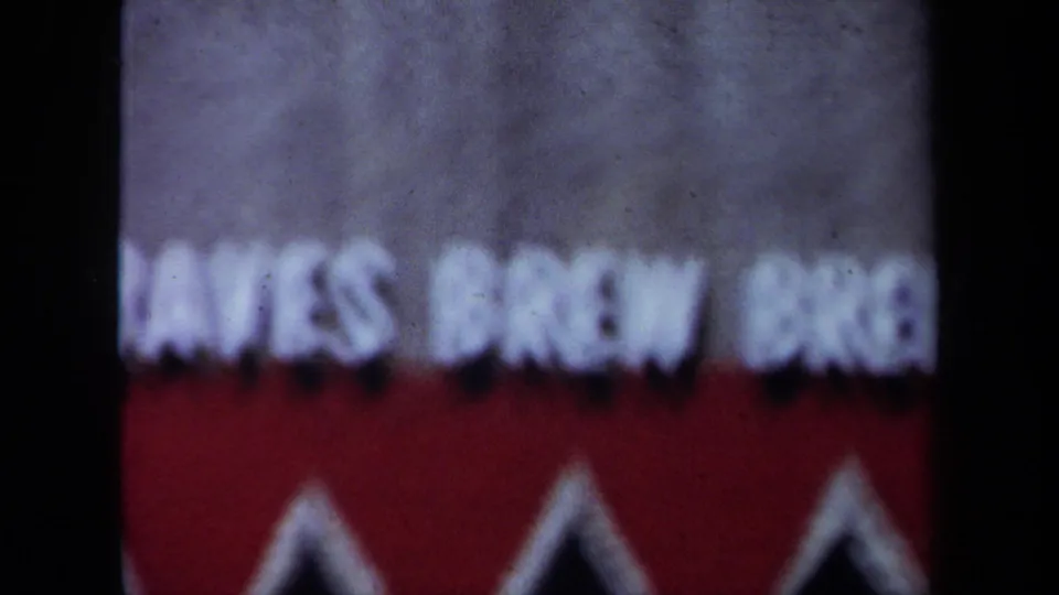 Final 1971 California 8mm frame with the cropped sign falling back into soft focus against red and gray fields.