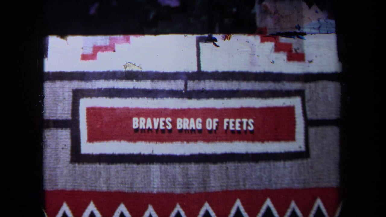 Woven textile with red, white, black, and gray pattern and the words BRAVES BRAG OF FEETS.
