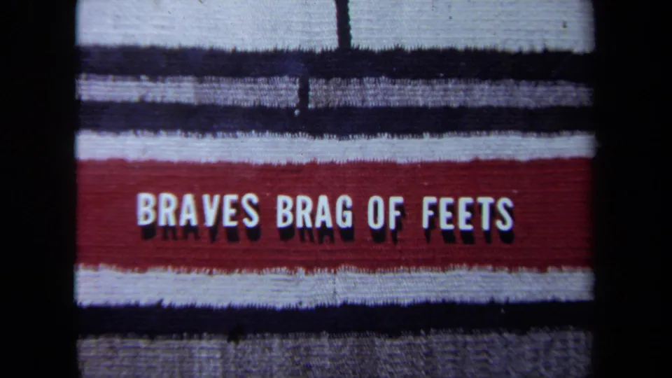 Tight 8mm close-up of the textile lettering, with the red band and white BRAVES BRAG OF FEETS text dominating the frame.