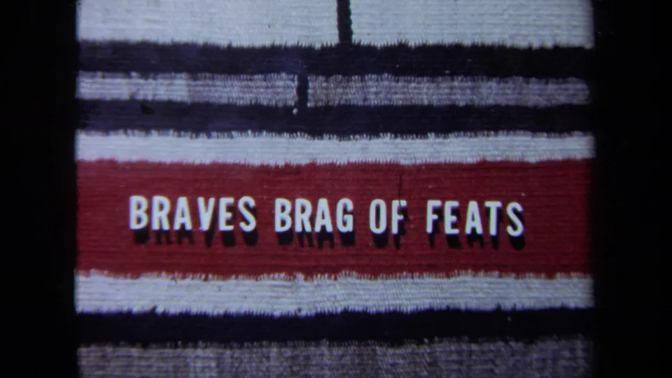 1971 California 8mm frame with a red-and-white sign reading "BRAVES BRAG OF FEATS" against dark film borders.