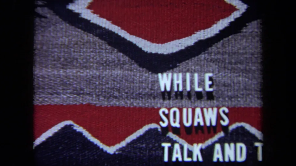1971 California 8mm frame where the white phrase has shifted downward over the patterned textile and is partly cut off at the bottom.