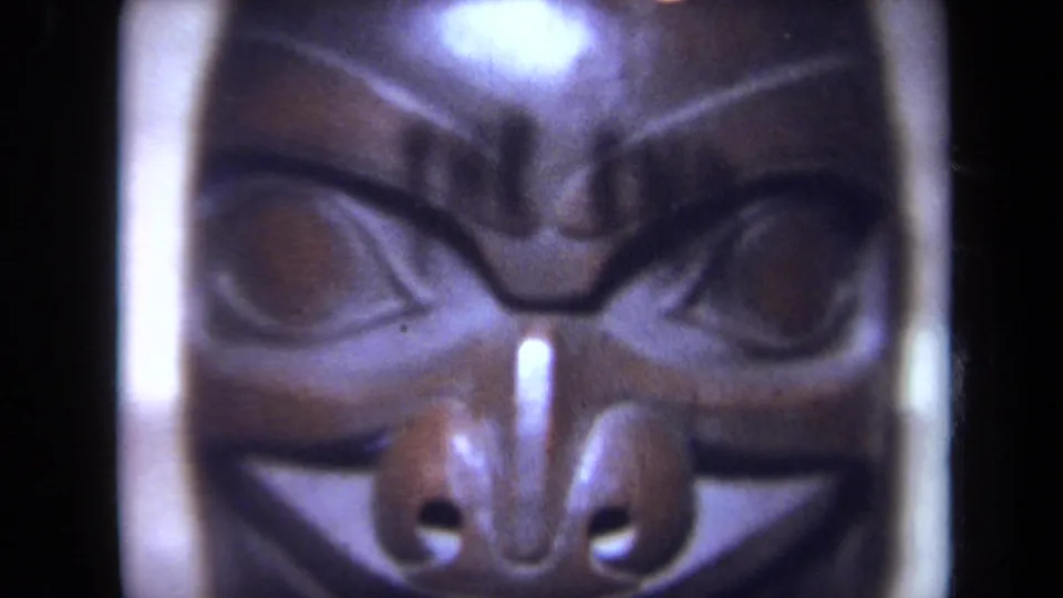 A second close-up of the carved wooden mask shows the face-like form in soft 8mm focus.