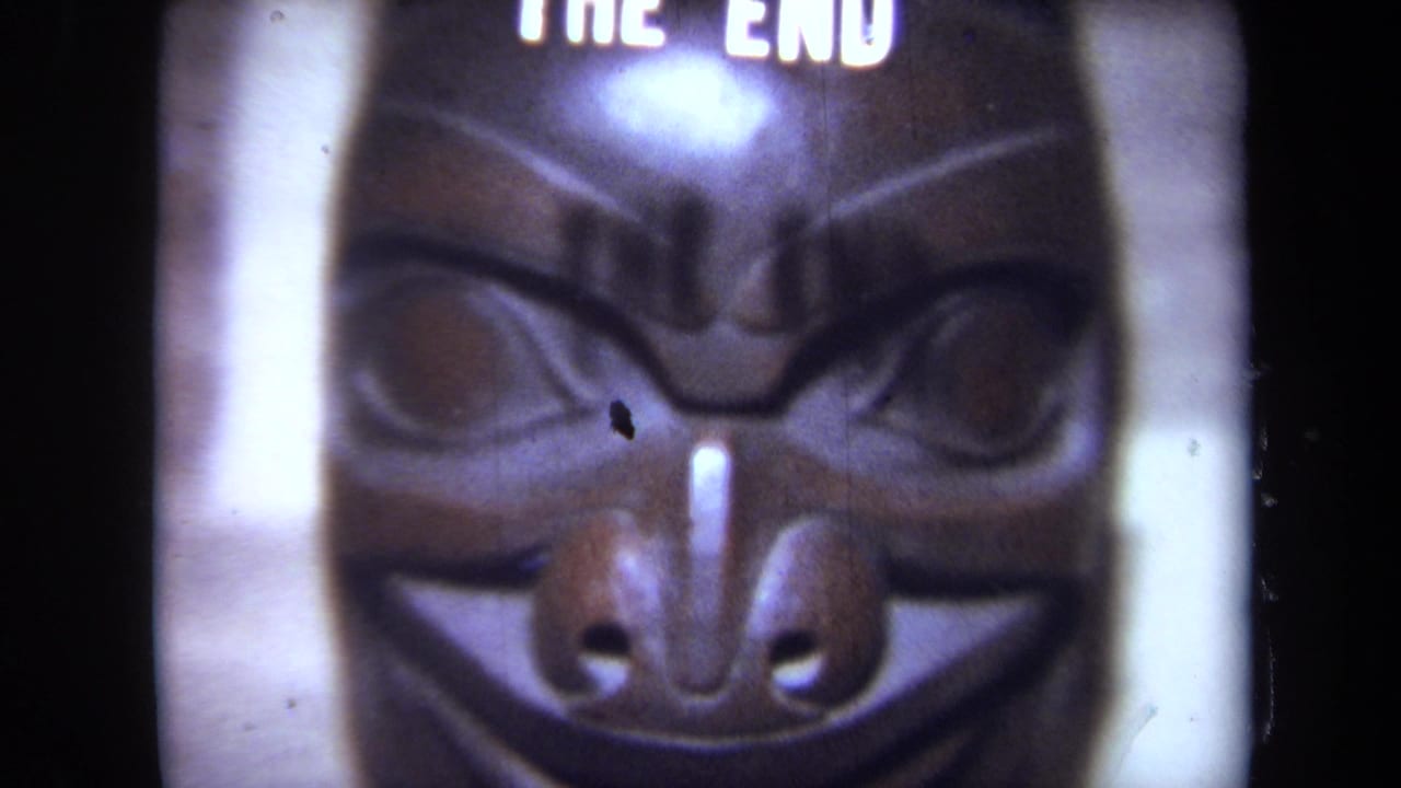 Soft close-up of a dark carved mask with partial THE END text at the top.