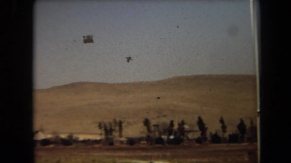1971 Laguna Hills 8mm view of an arid hillside, low trees, and open sky from a sliding roadside perspective.