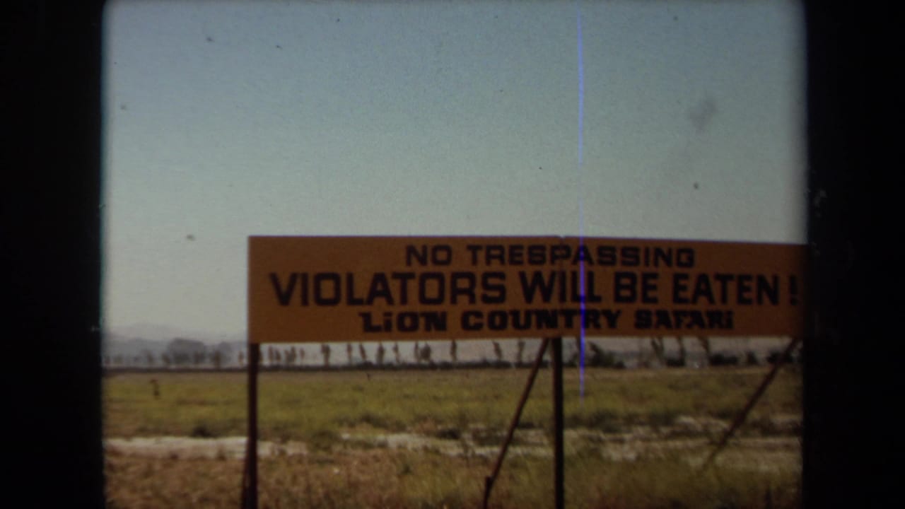 No trespassing sign with bold black lettering beside an open field.