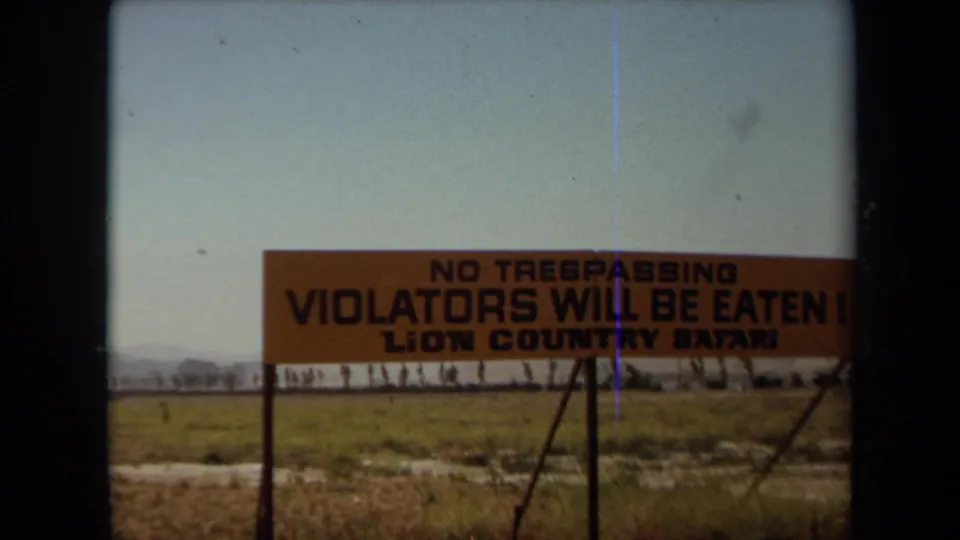 1971 Laguna Hills frame of the orange Lion Country Safari no trespassing sign, partly softened by 8mm film texture.
