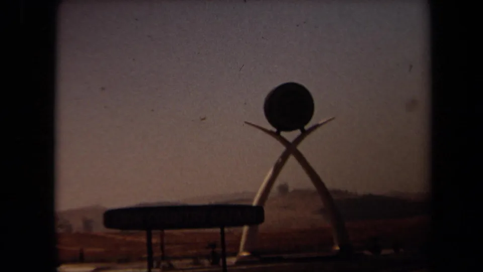 Lion Country Safari entrance marker with crossed tusk forms and a round top element, seen in 1971 home-movie footage.