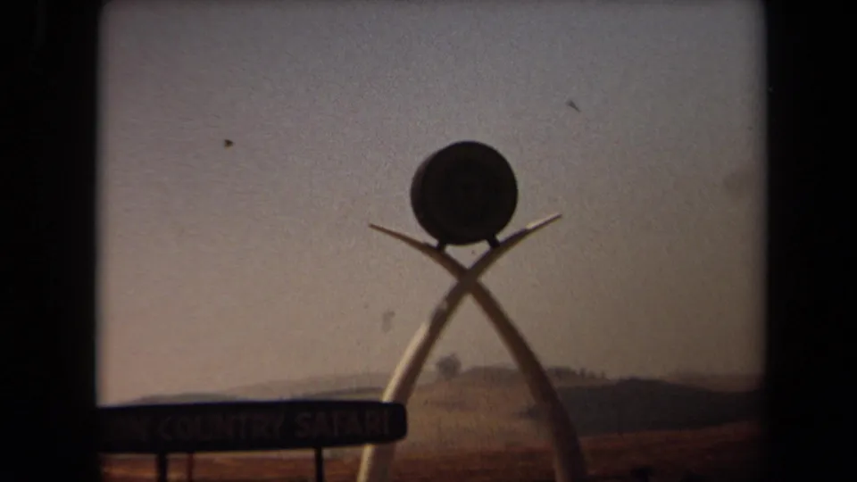 1971 Laguna Hills view of the Lion Country Safari entrance sign, partly framed by dark 8mm gate edges and a low horizon.