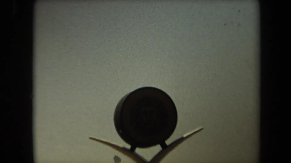 Final 1971 8mm frame holds on the Lion Country Safari entrance emblem, with hazy sky and a small passing dark shape near the supports.
