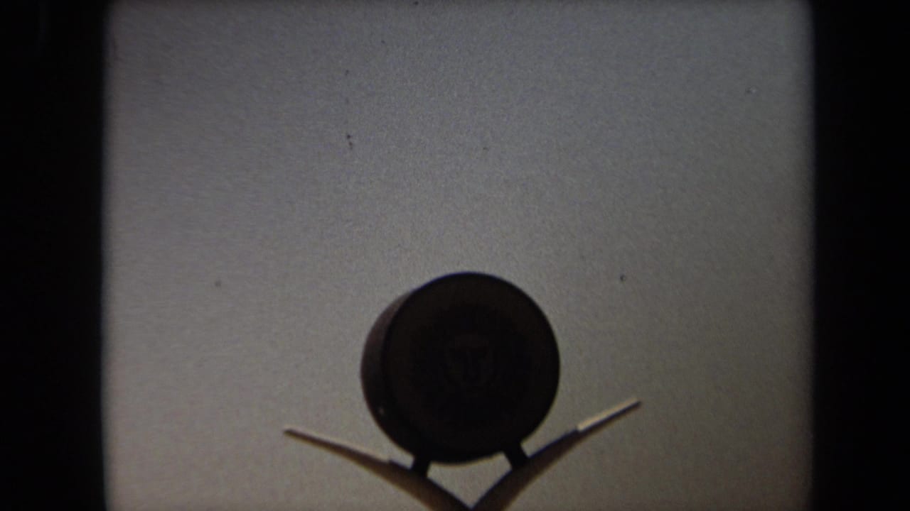 1971 Laguna Hills 8mm frame showing a dark round Kal-Kan Kennel Club sign or emblem against a light building wall.