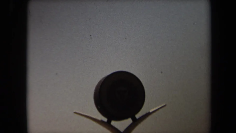 1971 Laguna Hills 8mm frame showing a dark round Kal-Kan Kennel Club sign or emblem against a light building wall.
