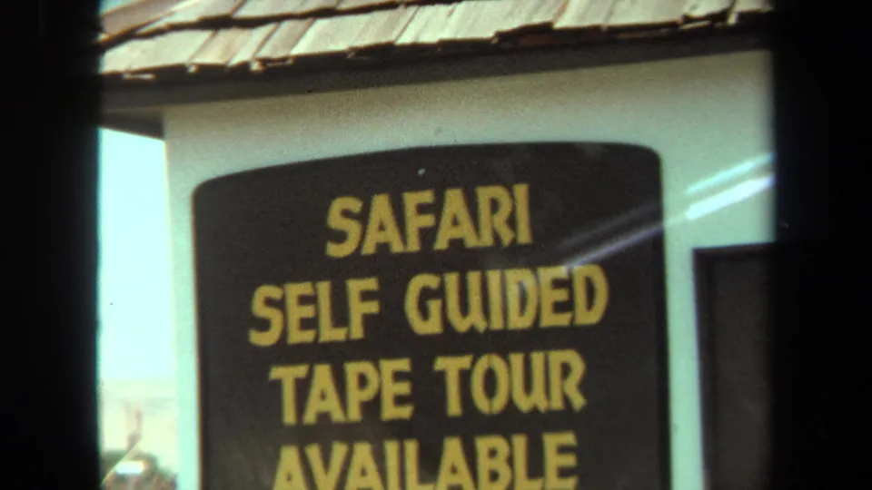 A black sign in Laguna Hills reads Safari Self Guided Tape Tour Available, filmed on 8mm in 1971.