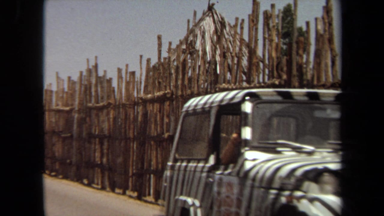 1971 Laguna Hills 8mm frame showing a vintage car near a tall wooden roadside fence.