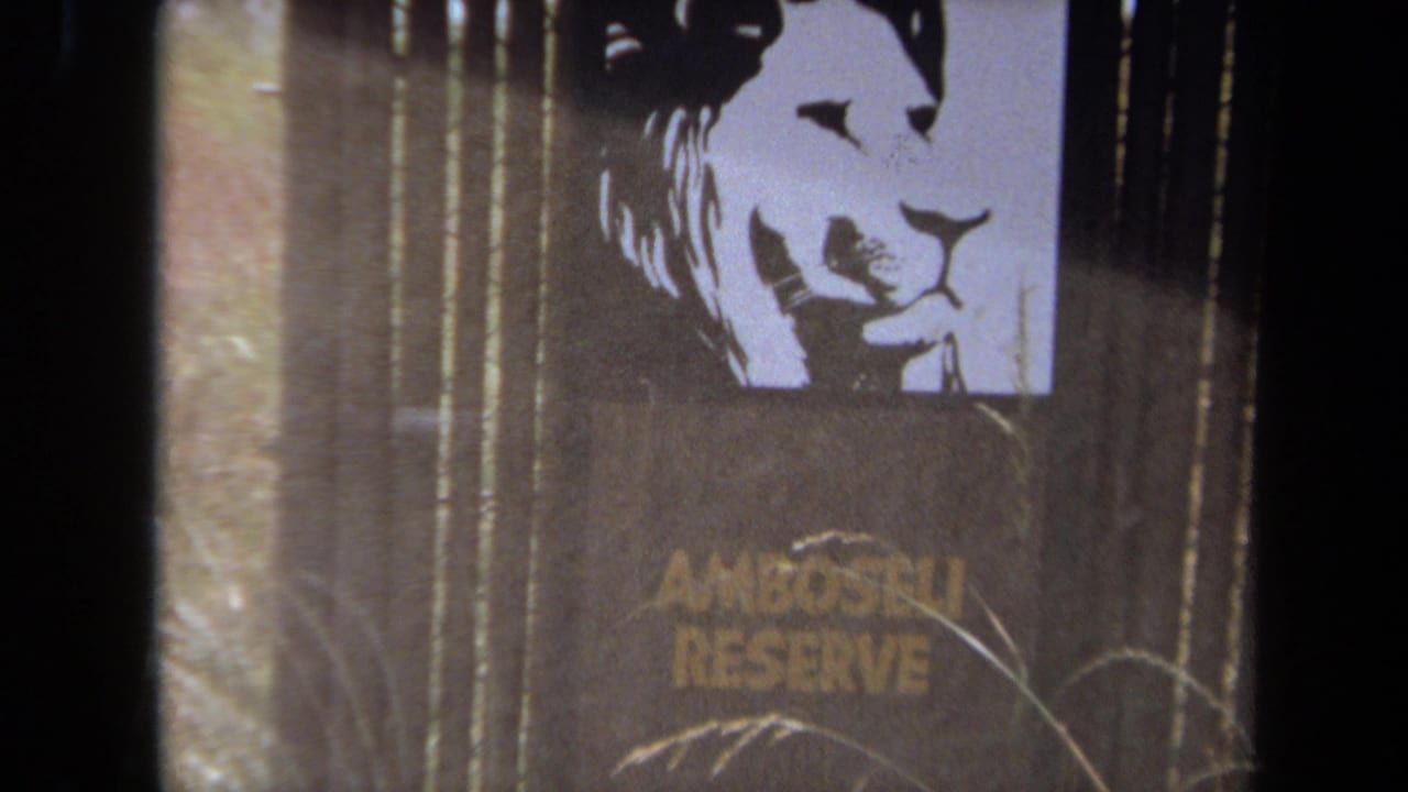 1971 8mm frame from Laguna Hills showing an Amboseli Reserve sign with a lion silhouette, partly obscured by dark film or framing edges.