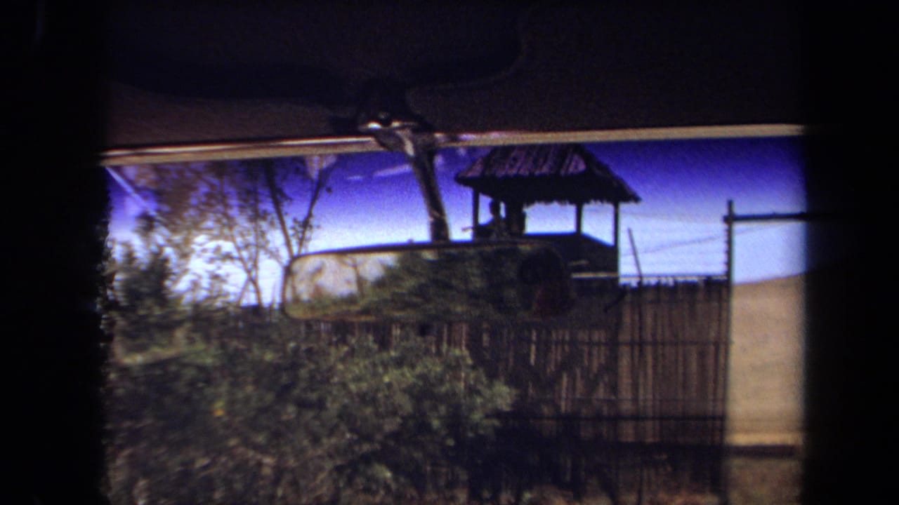1971 8mm car-window view, supplied as Laguna Hills, showing fencing, brush, and a small guard tower near a wildlife-park entrance.