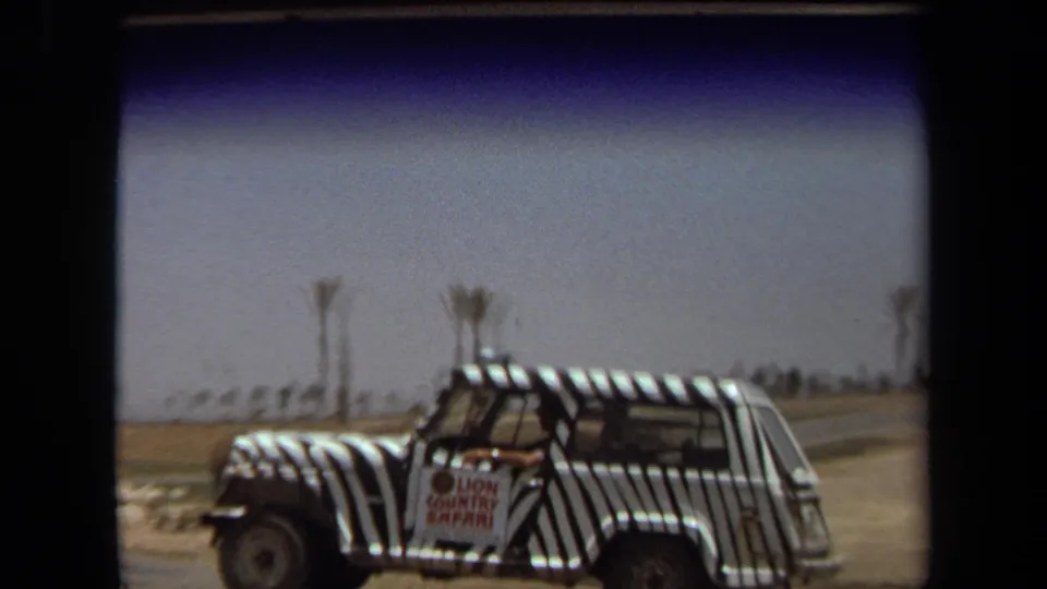 1971 Laguna Hills home-movie frame showing a zebra-striped safari vehicle with a Lion Country Safari sign under a bright sky.