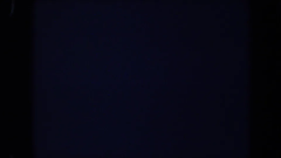 Underexposed 1971 8mm frame from the Laguna Hills zoo clip with only faint fence or structure detail visible.