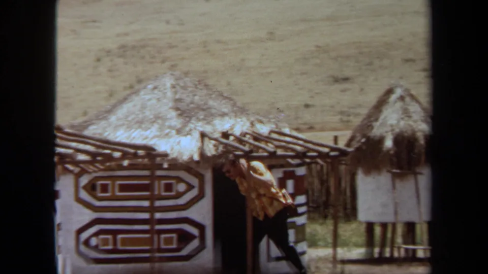 1971 Laguna Hills 8mm frame showing a visitor leaning near an exhibit doorway with bold geometric Ndebele-style wall patterns.