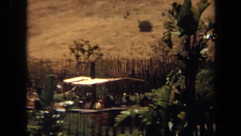 1971 8mm frame showing a covered attraction boat carrying passengers through a landscaped waterway in California.