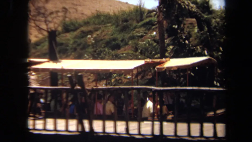 1971 Laguna Hills home-movie view of a riverboat ride, with passengers partly hidden below a bright canopy and dark rail fencing.