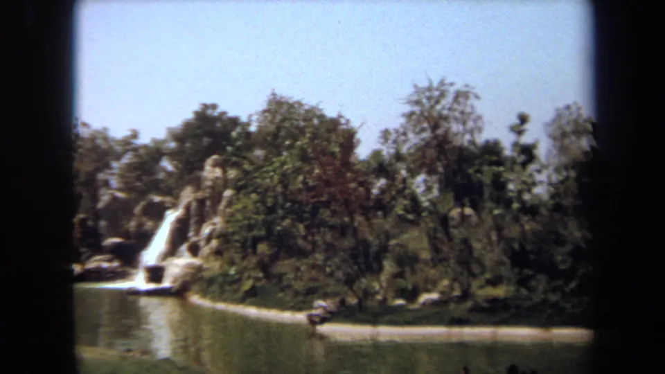 1971 Laguna Hills 8mm frame showing ducks on a pond beside trees, rock edging, and a small artificial waterfall.
