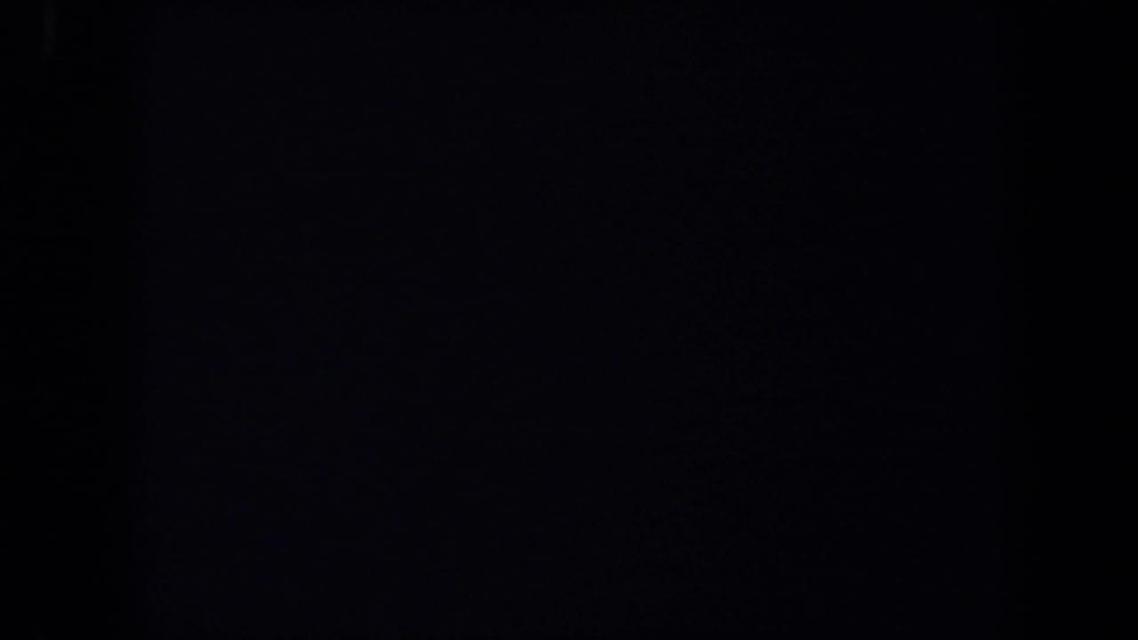 A mostly dark 8mm frame with the right side showing part of a docked ocean liner, streetlight, flags, and sky in 1971 California footage.