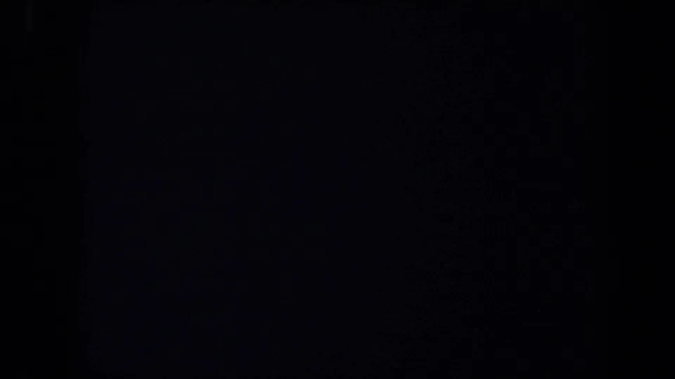 A mostly dark 8mm frame with the right side showing part of a docked ocean liner, streetlight, flags, and sky in 1971 California footage.