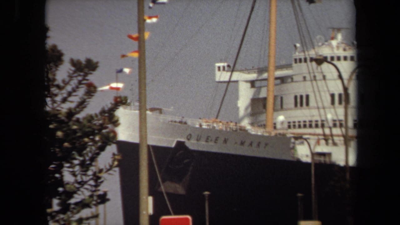 Bow and upper decks of the Queen Mary with signal flags, rigging, poles and dark framing.