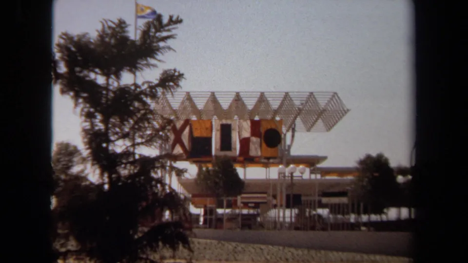 1971 Laguna Hills 8mm frame with the distinctive flagged structure set farther back behind trees and sandy landscaping.