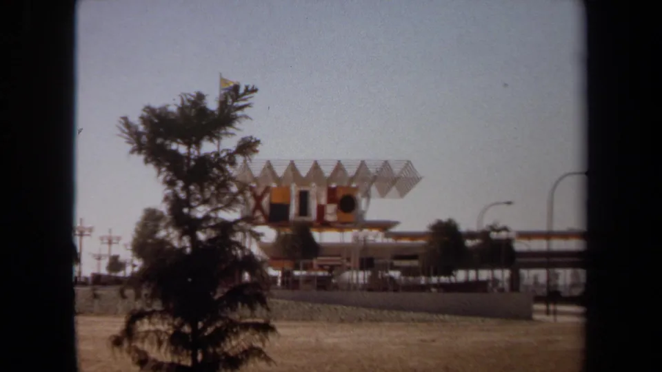 1971 Laguna Hills frame showing the structure at a distance with a tree in the foreground and open ground around it.