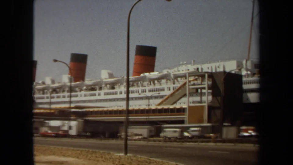 A later 1971 frame shows the liner's side and one prominent funnel, with dock equipment and roadside cars below.