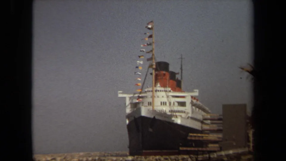 Closer 1971 Long Beach frame showing the ocean liner bow, white decks, dark hull, and signal flags.