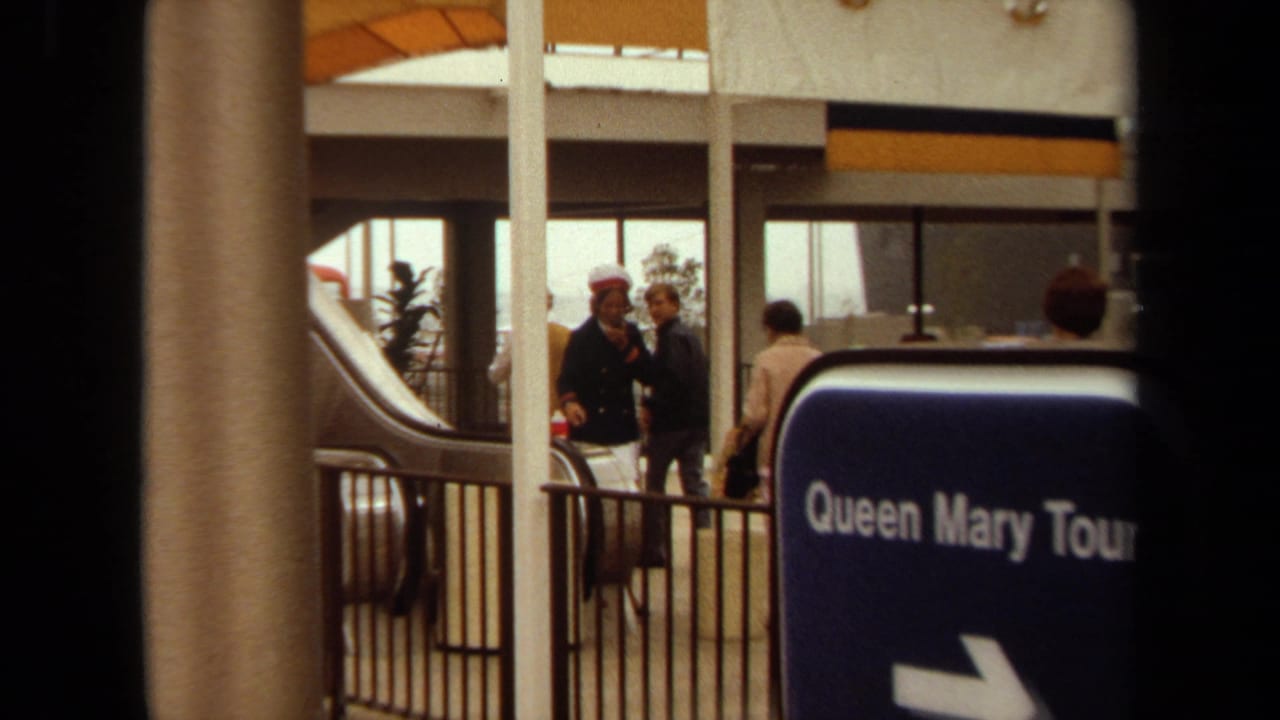 1971 Long Beach terminal view with passengers near an escalator and a blue Queen Mary Tour sign partly framed by dark structural bars.
