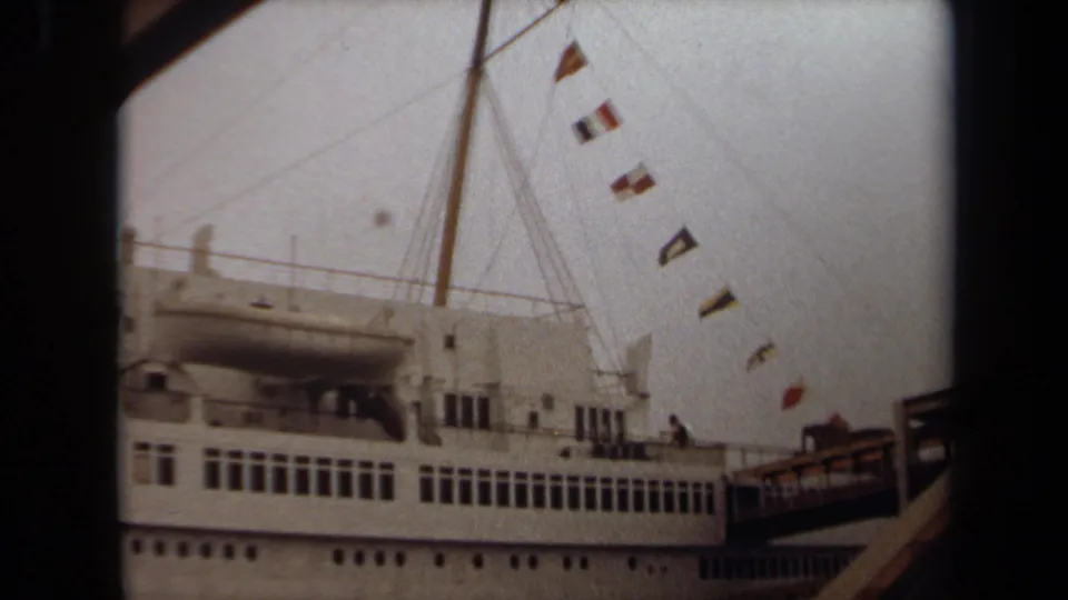 1971 Long Beach 8mm frame showing a docked white cruise ship with rows of windows, mast rigging, signal flags, and a gangway.